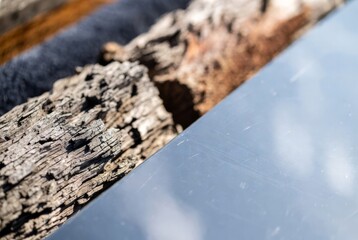 Fototapeta premium Close-up of weathered wood log beside shiny metal surface outdoors