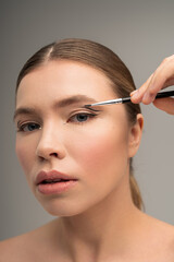 Fototapeta premium Captivating young woman applies makeup with precision in a serene beauty studio