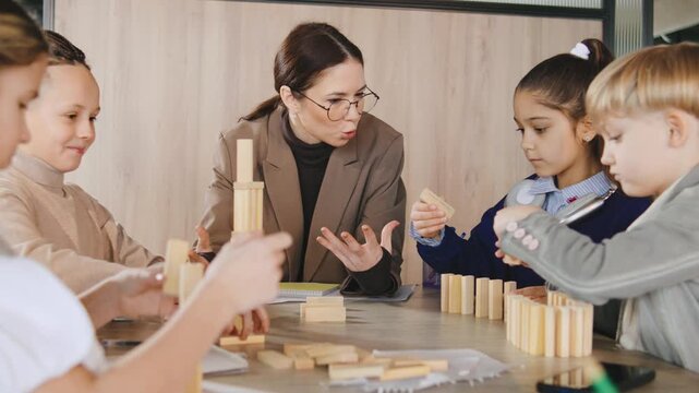 Group of children learning building skills with wooden blocks guided by a teacher in a classroom during a creative activity