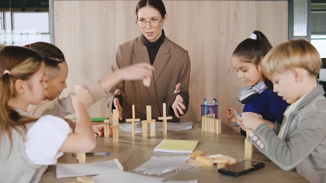 Children engage in building activity with teacher in classroom during afternoon session with various wooden blocks on table
