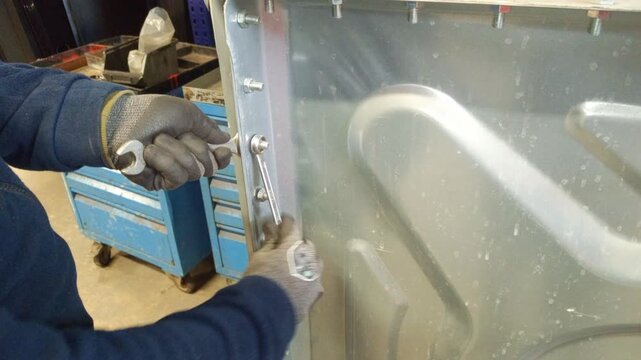 Close-up of a professional technician tightening loose nuts with a hand wrench in a metal warehouse