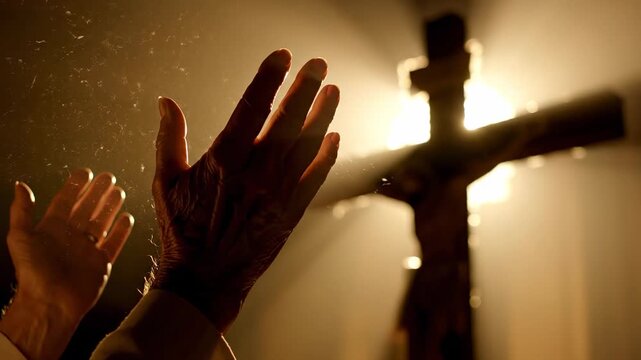 Hands reaching towards a cross with divine light rays and dust particles