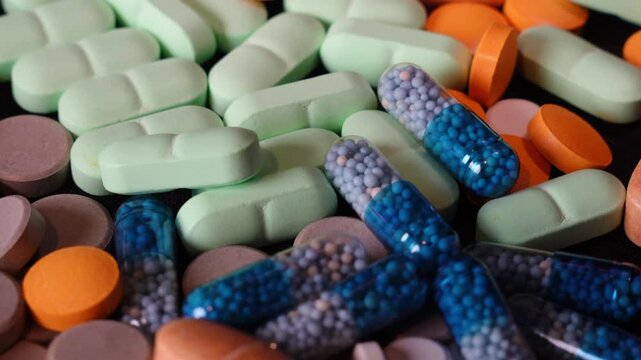 Full frame ECU macro of rotating colorful medical pills and tablets texture. Top view of pharmaceutical supplements on turntable