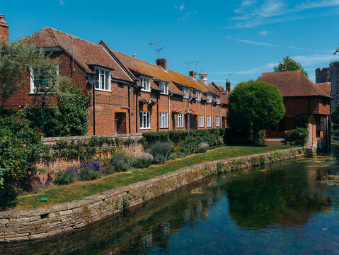 View of red brick buildings reflecting in the tranquil canal waters under a clear blue sky, a picturesque scene of serenity and heritage, Canterbury, England, United Kingdom.