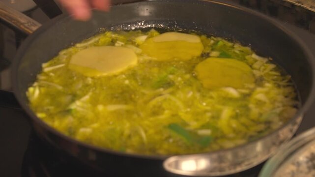Frying sliced ​​potatoes with leeks in a pan with virgin olive oil