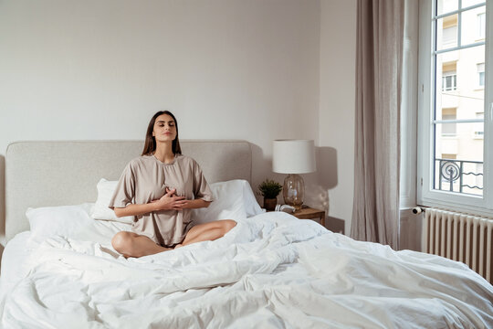Calm young woman practicing deep breathing meditation at home in bedroom. Mindfulness, emotional balance, anxiety relief, nervous system regulation, breathwork  concept