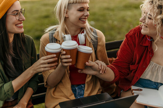 Group of young friends cheering with takeaway coffee cups