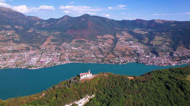 Italy Lake Iseo Monte Isola aerial drone fly-in to Santuario della Ceriola church on peak. Epic Alps mountains and scenic water view. Underrated Italian lake district travel scenery 4k landscape