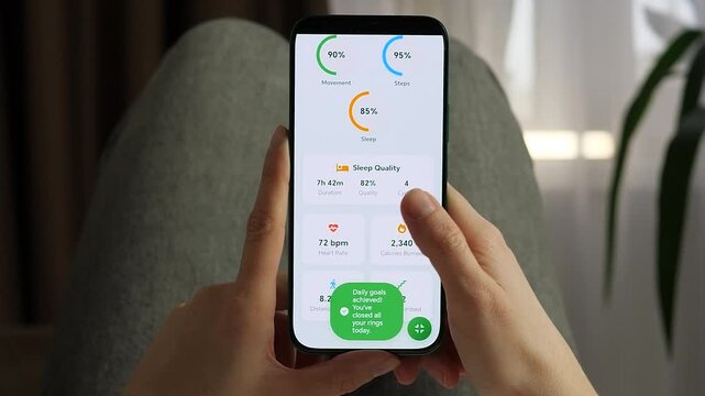 Close-up of a user closing all activity rings on a health app. A green notification celebrates daily goal achievement. Perfect for healthy lifestyle, motivation, and mHealth commercial projects.
