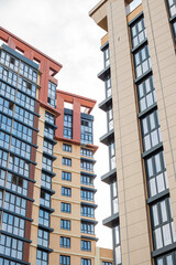 Fototapeta premium A low angle view of tall modern residential buildings against a cloudy sky. architecture, city living, apartment facade.
