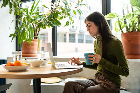 Woman working at cozy cafe table with breakfast items