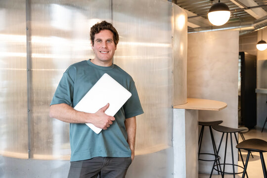 Man holding laptop in modern coworking space