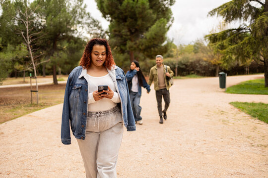 Woman walking in park checking smartphone