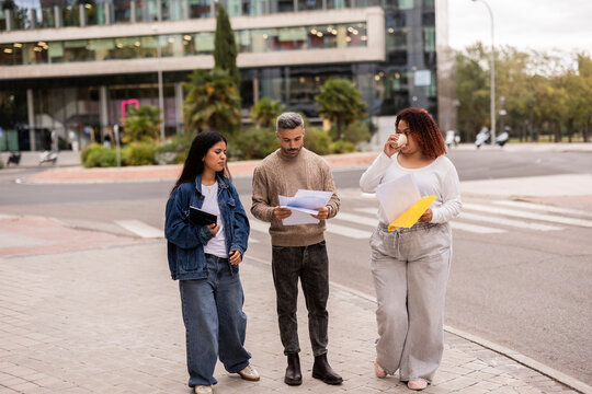 Multiethnic friends reviewing documents outdoors