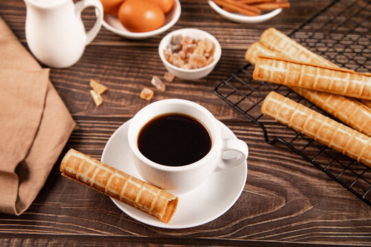 Cup of coffee with rolled wafer cookies on table