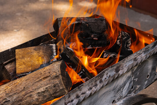 Glowing embers and flames in metal grill for summer barbecue