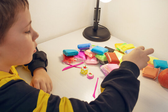 Child creating colorful modeling clay shapes at a desk