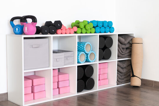 Organized fitness equipment on white shelving unit