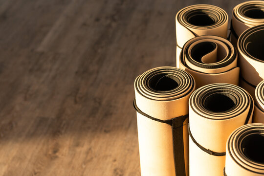 Rolled yoga mats stacked on a wooden floor