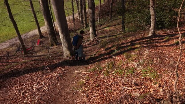 Rear view of parent and child walking down a steep forest path holding hands. Safe and calm outdoor family lifestyle moment in nature.