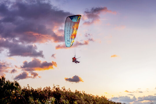 Paraglider soaring above scenic sunset landscape