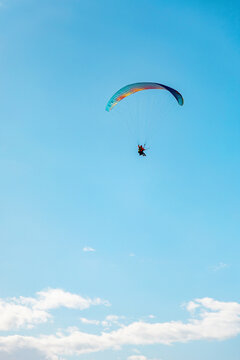 Paraglider soaring high in a clear blue sky