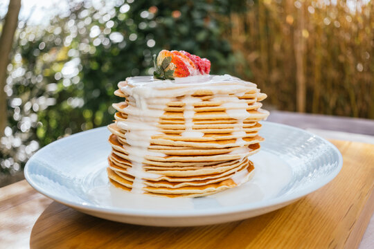 Stack of pancakes topped with strawberries and white chocolate