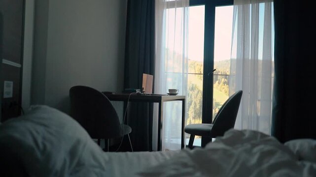 A cup of morning coffee on the table in a hotel room during breakfast. A businessman working and spending his morning meeting on a laptop while traveling on vacation. A trip to the mountains.