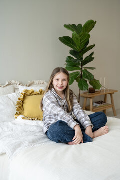 Young girl sitting on bed in cozy bedroom setting