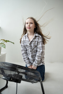 Girl enjoys the cool breeze from an electric fan