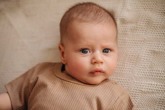 Adorable 3-month-old baby lying on knitted blanket