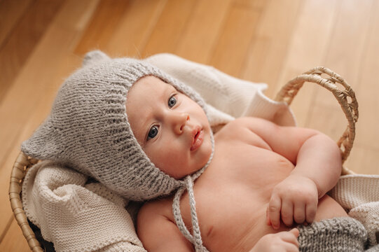 Adorable baby in a basket with knitted hat