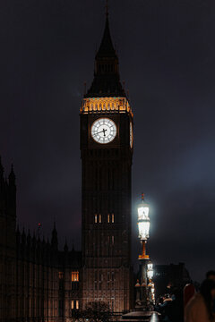 View of the iconic Big Ben clock tower piercing the dark London night, its illuminated face a beacon against the shadowy sky, London, England, United Kingdom.