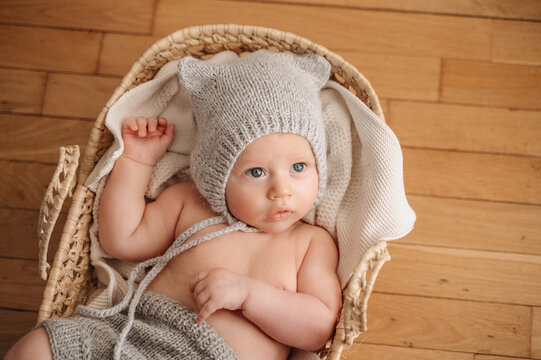 Adorable 3-month-old baby in cozy knit hat and basket
