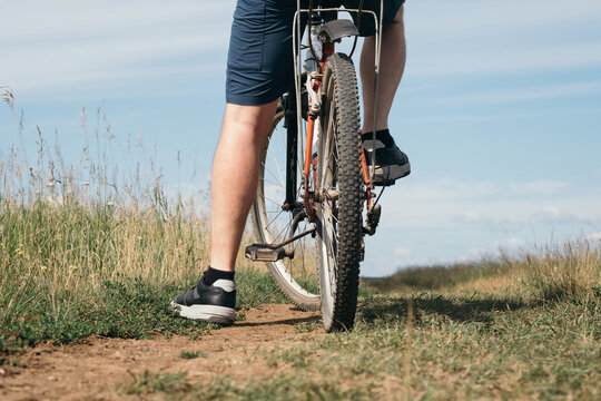 Cyclist on dirt path through green grass with blue sky