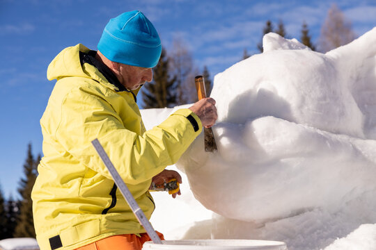 Man sculpting snow art outdoors in the Alps
