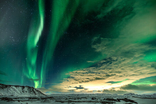 View of emerald ribbons dance across the inky sky, a celestial ballet illuminating the stark, snow-dusted landscape with an ethereal glow, Northern Lights, Reykjanes Peninsula, Iceland.