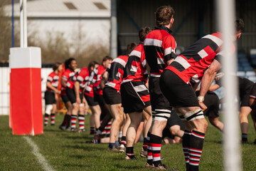 Obraz premium Rugby team playing on a grass pitch wearing red, black and white kit
