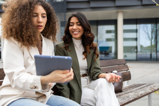 Women discussing business with digital tablet outside