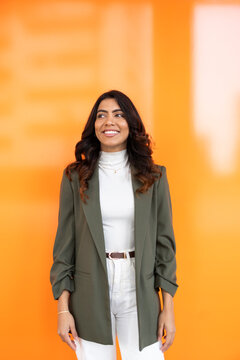 Confident woman standing against vibrant orange background