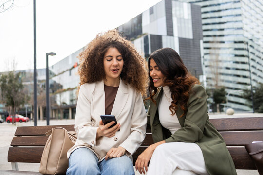 Women discussing business ideas on a city bench