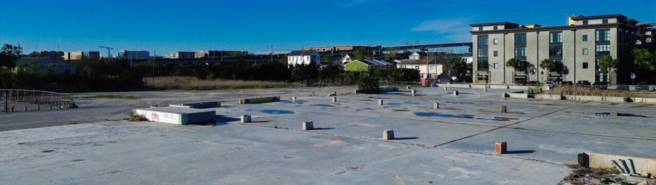 Panorama aerial open construction pad rests off Morrison Dr by NoMo corridor, apartments, commercial structures. Bright sky rough concrete textures, scattered materials, crisp building lines, SC