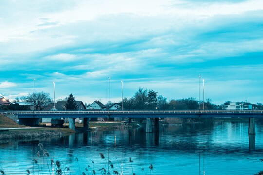 Blue Evening Bridge Over Bosut River With Reflections, Streetlights and Riverside Houses, Vinkovci, Croatia