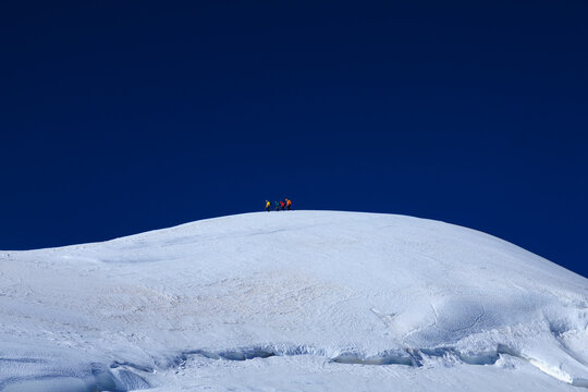 Mountaineers in rope team with crampons descending from summit Parrotspitze on mountain massif Monte Rosa with glacier in summer in Pennine Alps, Italy