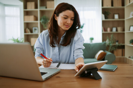 Woman working remotely at home office using laptop and tablet