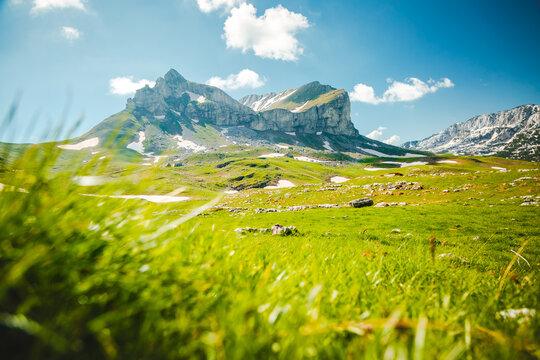 Majestic mountain peak rises above lush green valley under a clear blue sky. Location place Sedlena Greda, village Zabljak, Montenegro, Balkans, Europe.