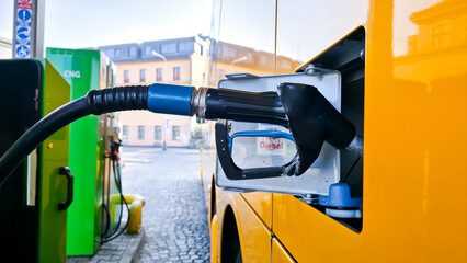 Yellow city bus refueling at fuel station, side view with nozzle connected. Urban transport maintenance scene, clean energy or diesel service concept, modern public transportation infrastructure. © VladyslavShcherbakov