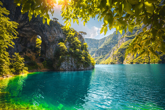 Perfect emerald waters flow beneath a stunning arch in a serene mountains filled with vibrant greenery. Location place Montenegro, Balkans, Europe.