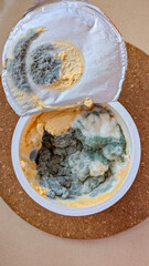 Moldy spoiled leftovers in plastic container with opened lid, unsafe food contamination and disgusting mood