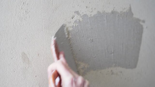 Applying putty to a plastered wall with a metal spatula producing a sharp squeaky sound, ASMR construction

